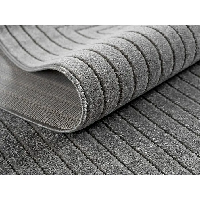 Outdoor-Teppich Nova II - Silver, Durchmesser: 80 cm, 100 % Polypropylen - Nahaufnahme eines gerollten, grauen Teppichs mit einem subtilen Streifenmuster, der eine weiche und strukturierte Oberfläche zeigt.