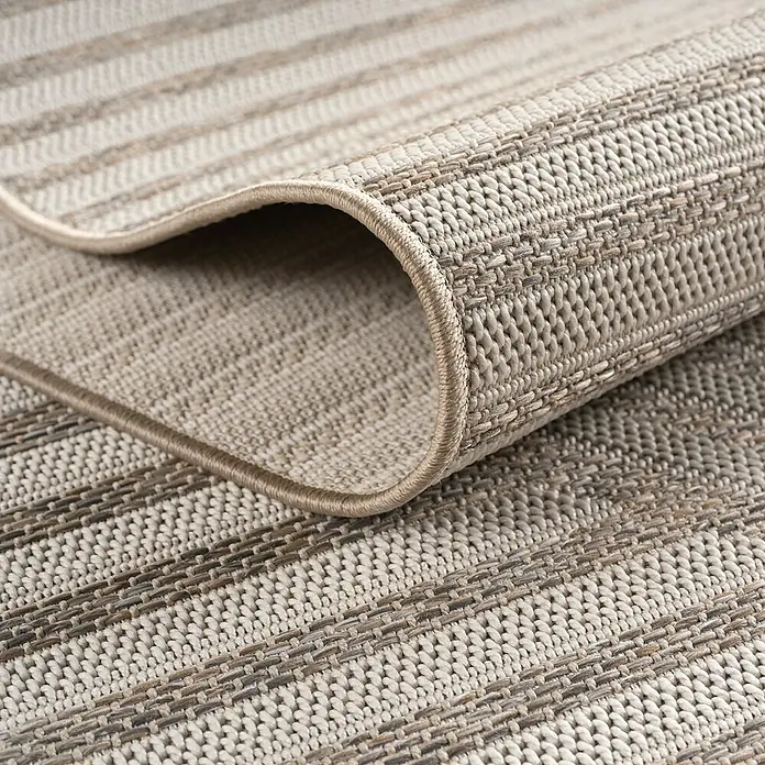 Outdoor-Teppich Desert 1301 - Beige, Durchmesser: 120 cm, 100 % Polypropylen - Nahaufnahme eines gestreiften Teppichs mit aufgerolltem Rand, der die Textur und das Design hervorhebt.