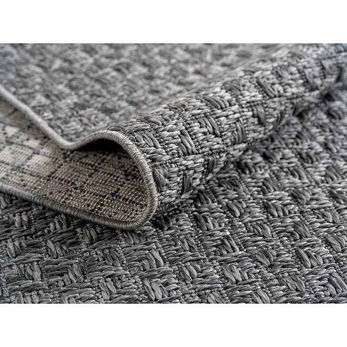 Outdoor-Teppich Ibiza III - Grau, 170 x 120 cm, 100 % Polypropylen - Detailaufnahme eines gerollten, grau melierten Teppichs mit gewebter Struktur. Der Teppichrand ist sauber eingefasst.