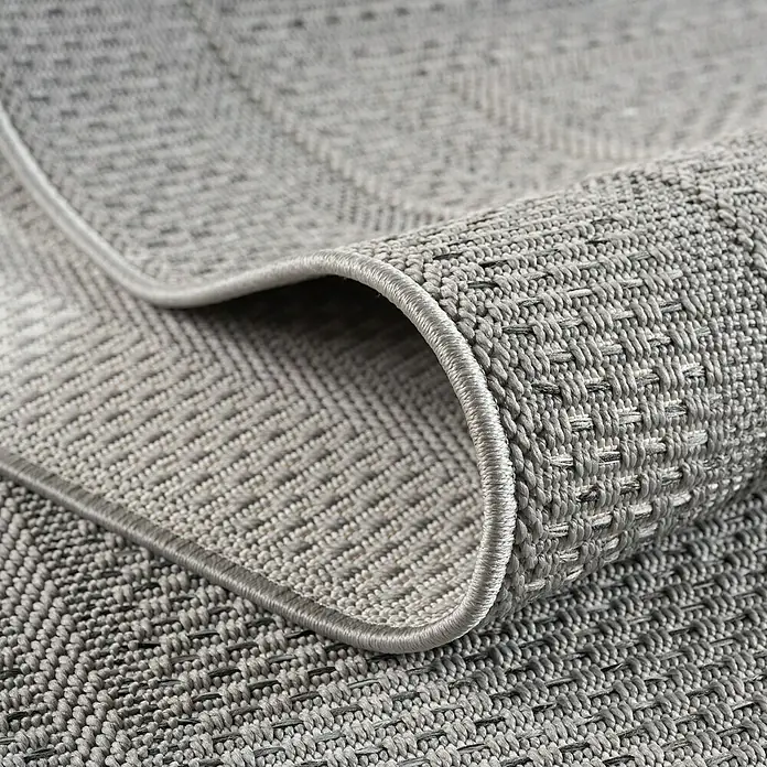 Outdoor-Teppich Desert 1304 - Grau, Durchmesser: 160 cm, 100 % Polypropylen - Detailaufnahme eines grauen Teppichs mit gewebter Textur und sauberer Einfassung, der ein modernes Designelement hervorhebt.
