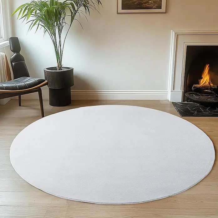 Kurzflorteppich Joy - Weiß, Durchmesser: 200 cm, 100 % Polyester - Ein weißer runder Teppich liegt in einem Wohnzimmer mit Kamin und Zimmerpflanze. Er verleiht dem Raum eine gemütliche Atmosphäre.
