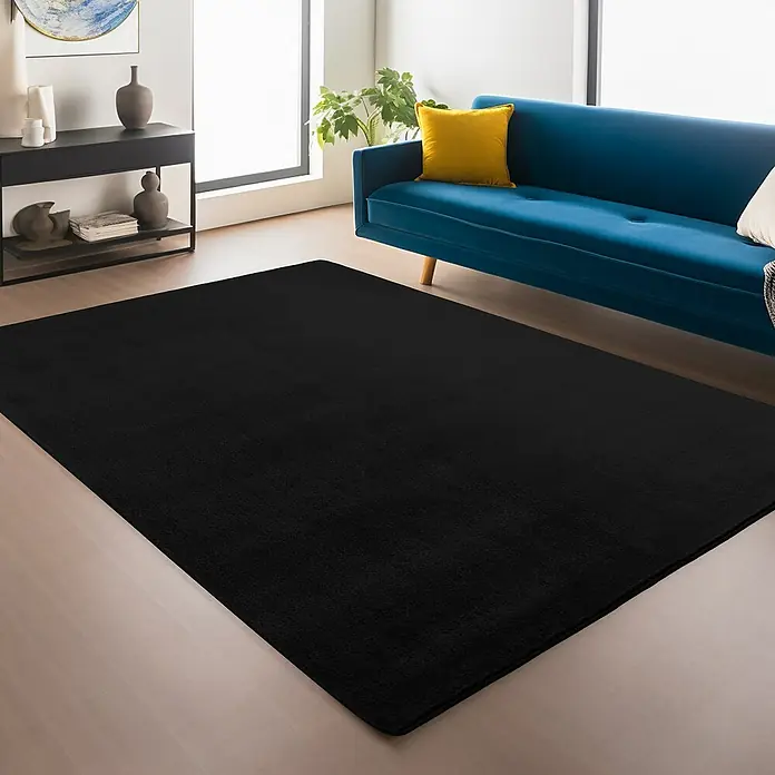 Kurzflorteppich Joy - Schwarz, 220 x 160 cm, 100 % Polyester - Schwarzer Teppich im Wohnzimmer mit blauer Couch und schwarzem Sideboard. Der Teppich ist der zentrale Blickfang.