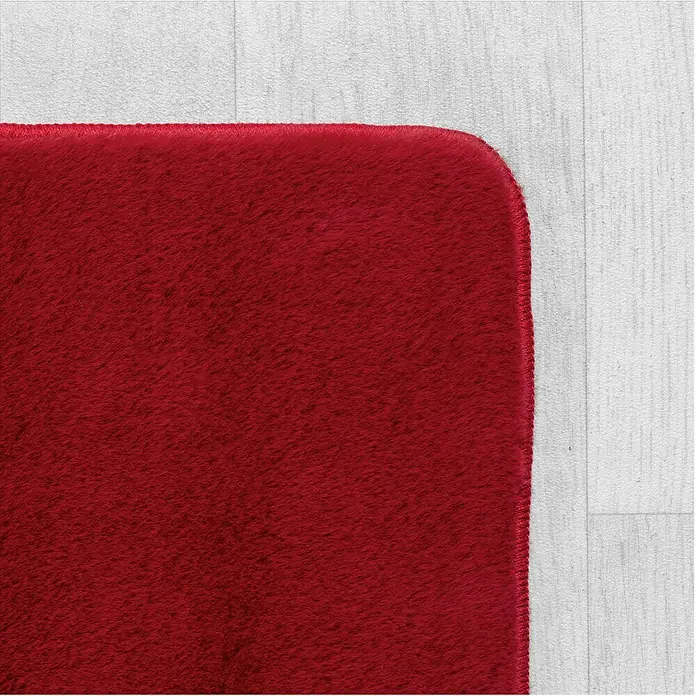 Kurzflorteppich Joy - Rot, 280 x 200 cm, 100 % Polyester - Nahaufnahme eines weichen, roten Teppichs mit abgerundeter Ecke auf einem hellen Holzboden. Der Teppich ist flauschig und strukturiert.