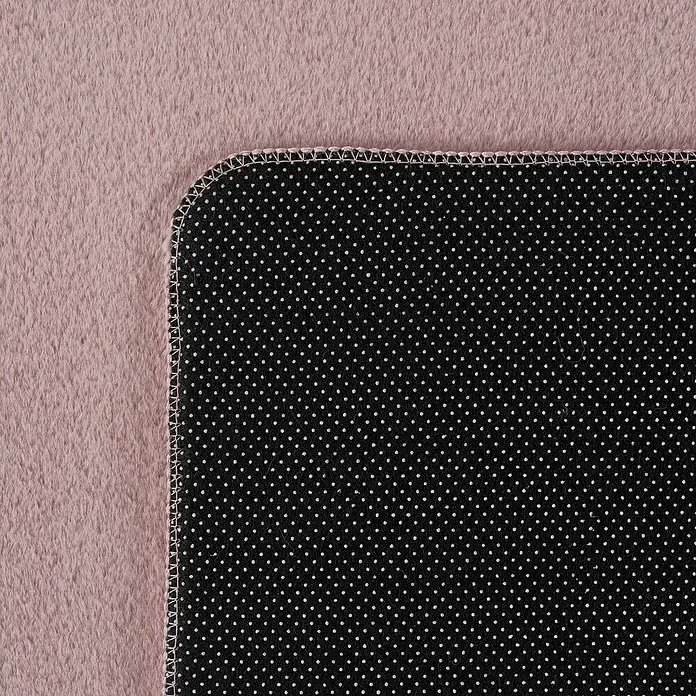 Kurzflorteppich Joy - Rosa, 100 x 60 cm, 100 % Polyester - Detailaufnahme einer weichen, rosafarbenen Decke mit schwarzer Unterseite mit weißen Punkten und einem dekorativen Stichrand.
