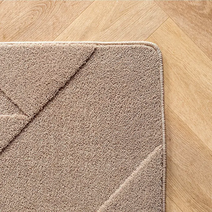Kurzflorteppich Pompei 1613 - Beige, 230 x 160 cm, 100 % Polyester - Detailansicht einer beigen Badematte mit geometrischem Muster auf hellem Holzboden. Die Matte hat eine feine, strukturierte Oberfläche.