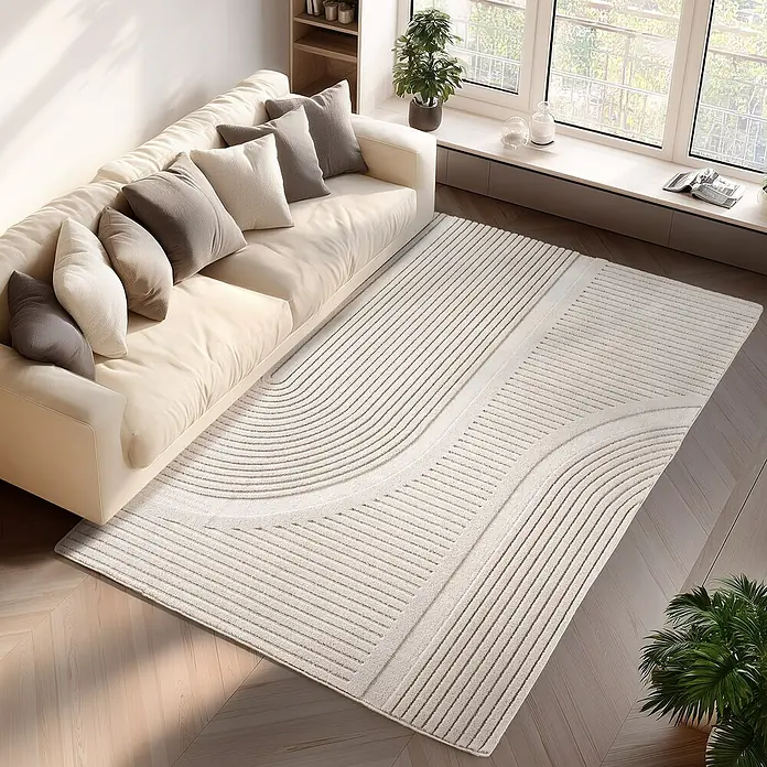 Kurzflorteppich Pompei 1612 - Creme, 340 x 240 cm, 100 % Polyester - Beige Couch mit dekorativen Kissen auf einem elfenbeinfarbenen Teppich mit abstraktem wellenförmigen und linearem Design.