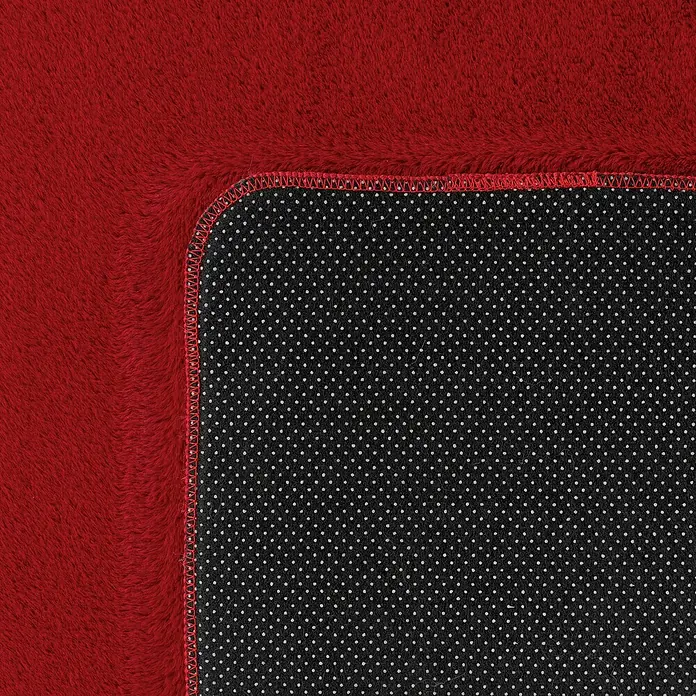 Kurzflorteppich Joy - Rot, 280 x 200 cm, 100 % Polyester - Nahaufnahme einer roten, flauschigen Teppich-Ecke mit rutschfester Unterseite, ideal für ein gemütliches Zuhause.
