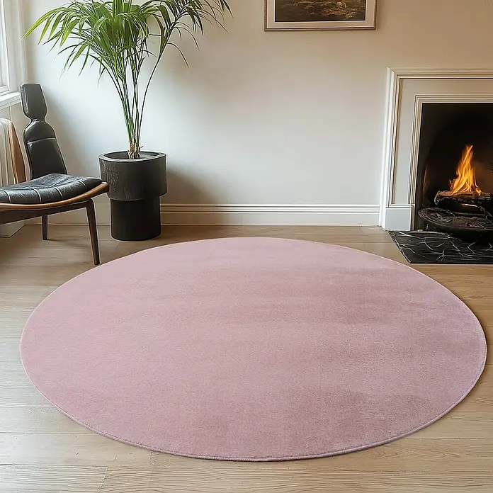 Kurzflorteppich Joy - Rosa, Durchmesser: 160 cm, 100 % Polyester - Ein weicher, runder, rosafarbener Teppich liegt auf einem Holzboden und verleiht dem Raum Wärme und Stil. Der Teppich ergänzt die Einrichtung und den Kamin perfekt.