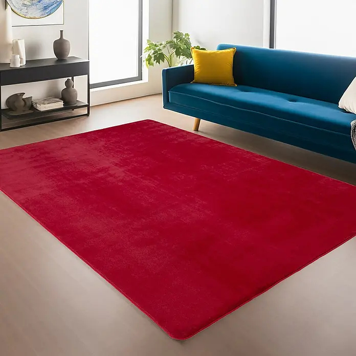 Kurzflorteppich Joy - Rot, 280 x 200 cm, 100 % Polyester - Roter Teppich im Wohnzimmer unter einem blauen Sofa, der dem Raum einen Farbtupfer verleiht.