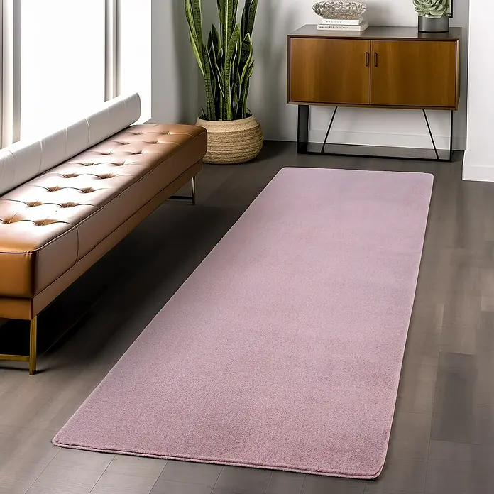 Kurzflorteppich Joy - Rosa, 100 x 60 cm, 100 % Polyester - Ein rechteckiger, flauschiger, lavendelfarbener Teppich liegt auf einem Holzboden und verleiht dem Raum Wärme und Stil.
