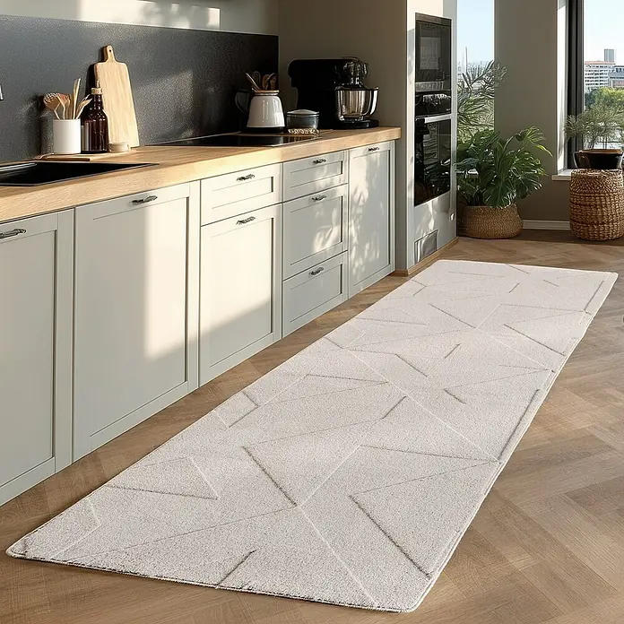 Kurzflorteppich Pompei 1613 - Creme, 250 x 80 cm, 100 % Polyester - Ein cremefarbener Teppich mit geometrischen Mustern liegt in einer modernen Küche auf einem Holzboden. Er verleiht dem Raum Wärme und Stil.