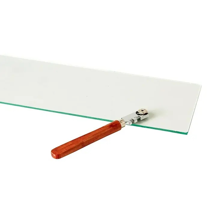 Juliana Glasschneider - 1 Stk. - Glasschneider mit Holzgriff liegt auf einer Glasscheibe, bereit zum Schneiden für Bastel- und Handwerksprojekte.