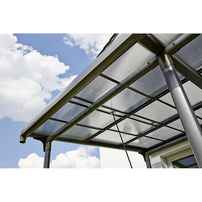 Sunfun Pérgola adosada Sera - An x Pr: 400 x 300 cm, Antracita, Aluminio - Un primer plano de un moderno toldo con un techo traslúcido y elegantes soportes de metal contra un fondo de cielo azul con nubes.