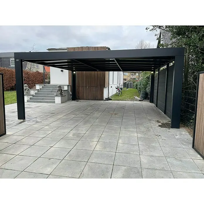 Carport Cubus - Außenmaß inkl. Dachüberstand (B x T): 5,8 x 5,5 m, Doppelcarport, Grau - Eine moderne, schwarze Terrassenüberdachung mit hellgrauen Pflastersteinen im Außenbereich. Die Konstruktion bietet Schutz vor Sonne und Regen.