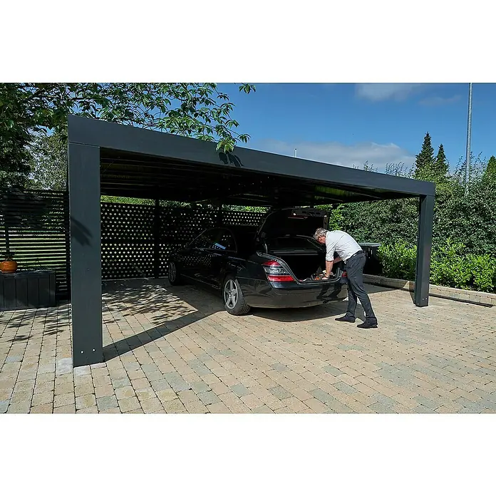 Allview Carport Cubus Lange Ausführung (Doppel) - Außenmaß inkl. Dachüberstand (B x T): 5,8 x 5,8 m, Grau - Mann hantiert am Kofferraum eines schwarzen Autos unter einem modernen Carport mit grauer Überdachung und Pflastersteinen.