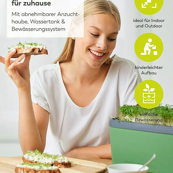 Gusta Garden Anzucht-Set Chili-Starter-Set - 5 -tlg., Dunkelgrün - Eine Frau genießt ein mit Sprossen belegtes Brot neben einem Zimmergewächshaus. Ideal für Indoor und Outdoor mit Bewässerungssystem.