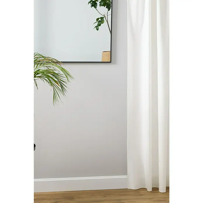 Espejo de pared Alina Baby - 80 x 85 cm, Negro - Interior minimalista con planta de interior, espejo con marco negro y cortina blanca, creando un ambiente sereno y natural.