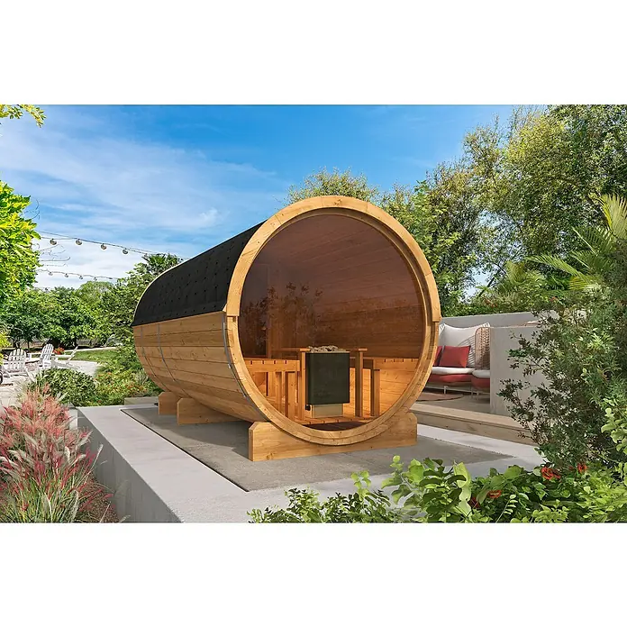Tuindeco Fasssauna - L x B x H: 400 x 205 x 220 cm, Ohne Ofen, Großes Panoramafenster - Ein Fass-Sauna im Außenbereich mit Holzverkleidung und einem schwarzen Dach vor einer üppigen grünen Kulisse.