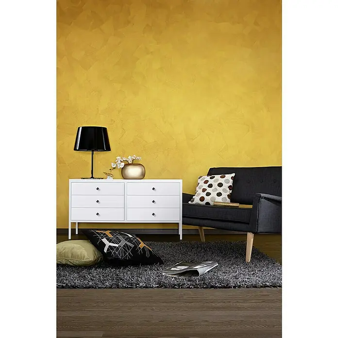 SCHÖNER WOHNEN-Farbe Trendstruktur Farbeffektputz Metall-Optik Effektfarbe - Mattgold, Matt, 2,5 l - Das Bild zeigt ein modernes Wohnzimmer mit einer weißen Kommode und einem stilvollen Sessel auf einem grauen Teppich.