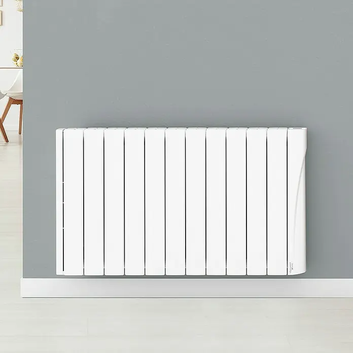 Voltomat Emisor térmico H WiFi II - 1.750 W, Blanco, 9,5 x 98 x 57,5 cm, Fluido - Primer plano de un radiador blanco sobre una pared gris, que ofrece calidez y confort a cualquier habitación.