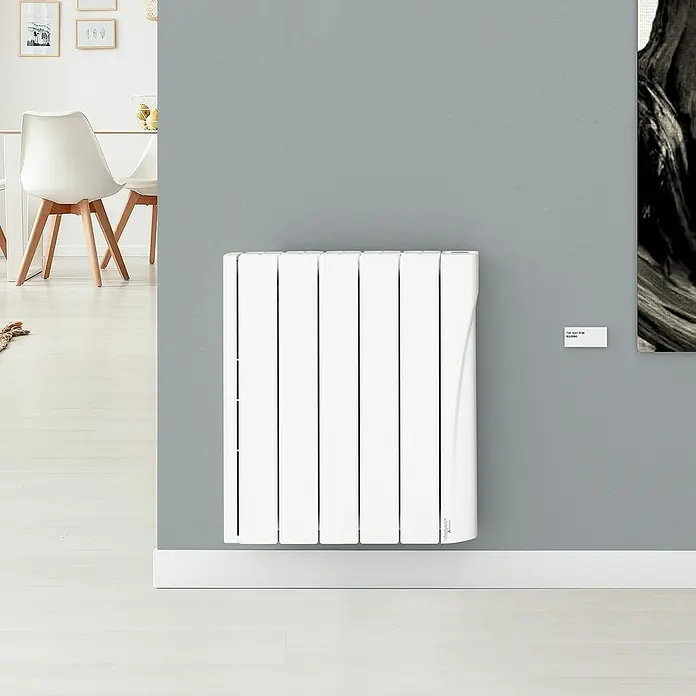 Voltomat Emisor térmico WiFi I - 750 W, Blanco, 9,5 x 50 x 57,5 cm, Cerámico - Un radiador blanco moderno está montado en una pared gris. Su diseño elegante se integra perfectamente en el espacio.