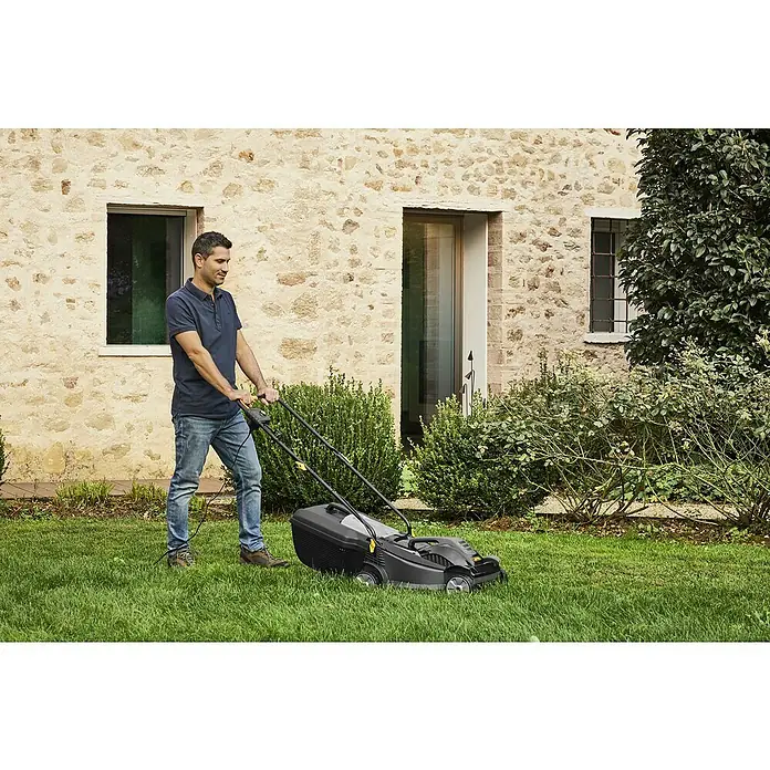 Alpina Elektro-Rasenmäher BL 380 E - 1.400 W, Schnittbreite: 38 cm - Ein Mann mäht den Rasen mit einem schwarzen Rasenmäher vor einem steinernen Haus.