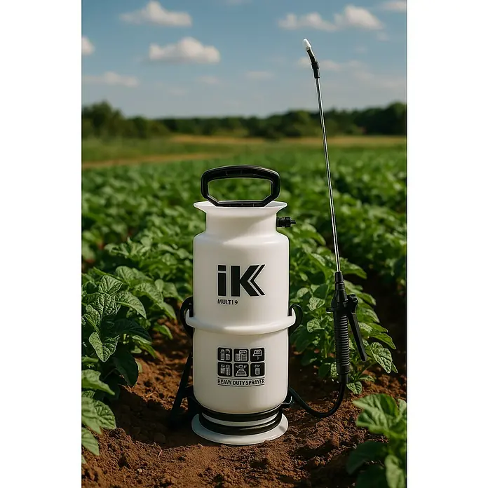 Matabi Pulverizador industrial IK 9 - 6 l, Blanco - Un pulverizador a presión IK Multi 9 blanco se encuentra en un campo de plantas verdes, ideal para jardinería y agricultura.