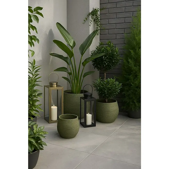 Farolillo metálico Arzilla - 13,5 x 13 x 34,5 cm, Negro - Escena decorativa al aire libre con jardineras verdes, faroles y plantas, creando un ambiente tranquilo y elegante para la vida al aire libre.