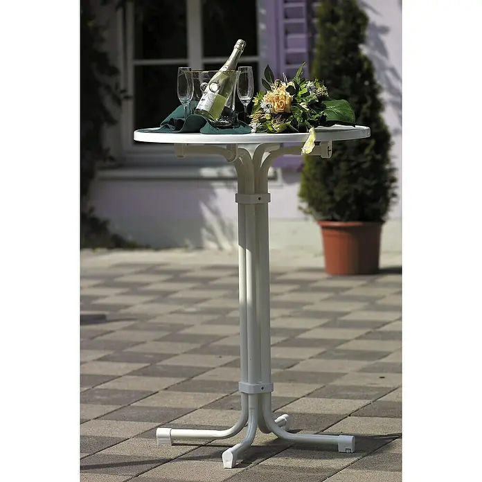 Barths Garten-Stehtisch rund Multiflex - Ø x H: 70 x 100 cm, Stahl, Rund, Weiß - Ein weißer Bistrotisch mit Sektkübel, Champagnerflasche, Gläsern, Servietten und Blumenstrauß im Freien.