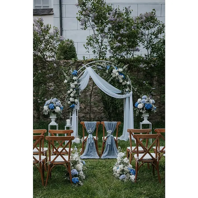 Stapelstuhl Crossback - 1 Stk., Ulmenholz, Braun, B x T x H: 48 x 47 x 89 cm - Hochzeitsdeko mit blau-weißen Blumenarrangements, einem weißen Bogen und dekorierten Stühlen auf einer grünen Wiese. Romantische Atmosphäre.