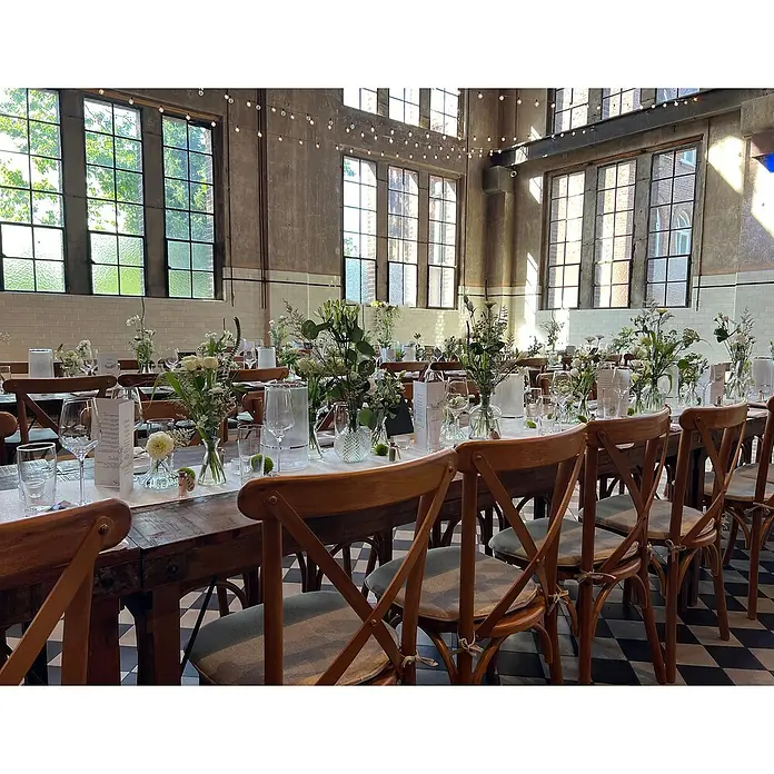 Stapelstuhl Crossback - 1 Stk., Ulmenholz, Braun, B x T x H: 48 x 47 x 89 cm - Festlich gedeckte Tische mit rustikalen Holztischen und eleganten Blumenarrangements in einer hellen, industriellen Location mit großen Fenstern.
