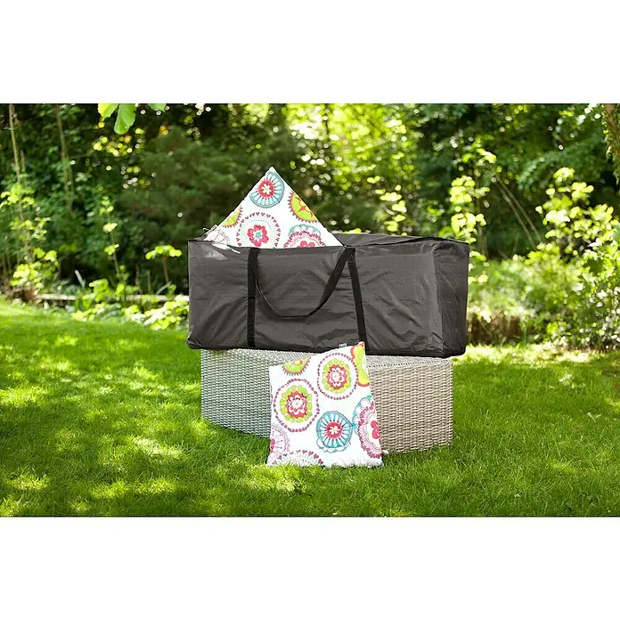 Barths Auflagen-Schutzhülle - L x B x H: 125 x 40 x 50 cm, Polypropylen, Hellgrau - Bild zeigt eine graue Aufbewahrungstasche mit bunten Kissen auf einem Rattanhocker im Garten, ideal zur Aufbewahrung von Gartenmöbelkissen.
