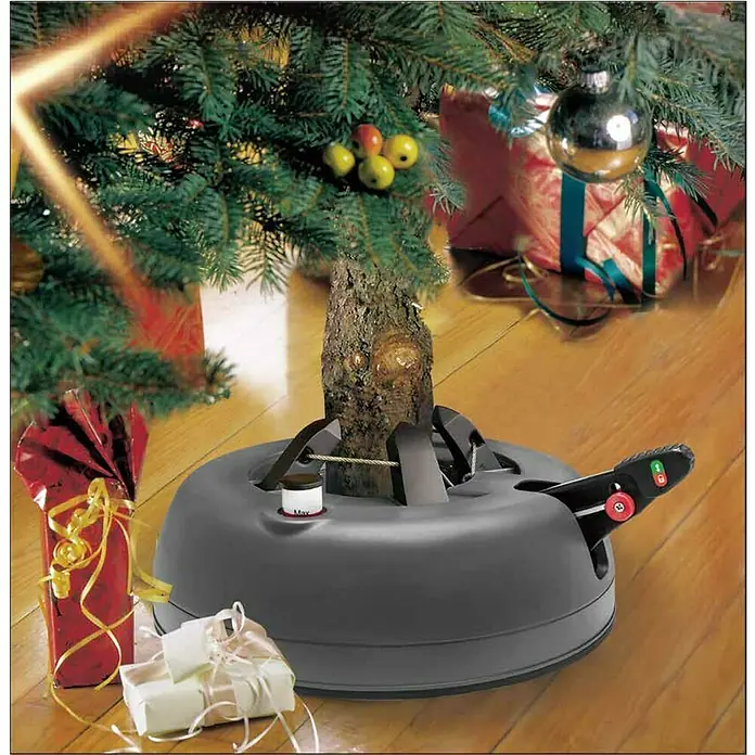 Christbaumständer Star-Max - Max. Baumlänge: 1,8 m, Max. Stammdurchmesser: 10 cm, Fassungsvermögen Wassertank: 1,6 l, Fußhebel - Weihnachtsbaumständer aus grauem Kunststoff unter einem Weihnachtsbaum mit Geschenken auf einem Holzboden.