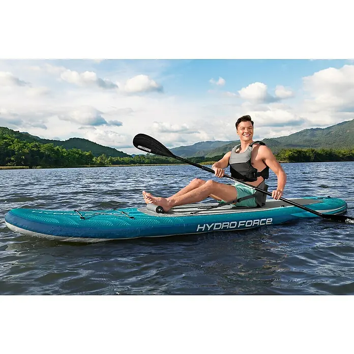 Bestway Hydro Force SUP-Board-Set Aqua Drifter™ mit Sitz - L x B x H: 335 x 91,5 x 15 cm, Nutzlast: 150 kg, Aufblasbar, Grün - Ein Mann paddelt auf einem Hydro Force SUP-Board auf einem See. Das Board ist blau und hat eine graue Standfläche.