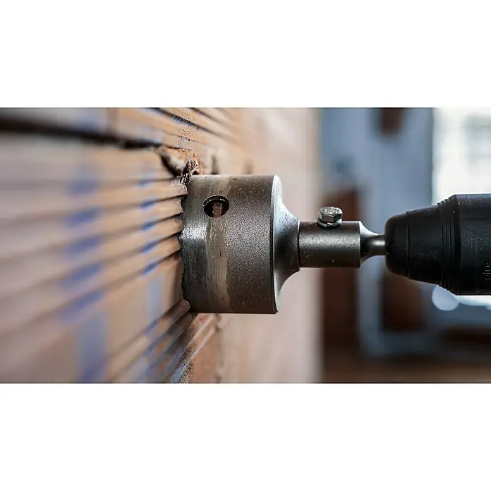 Craftomat Bohrkrone - Durchmesser Bohrer: 82 mm - Nahaufnahme einer Bohrmaschine mit Lochsäge beim Bohren eines Lochs in eine Ziegelwand, ideal für Bau- und Heimwerkerprojekte.