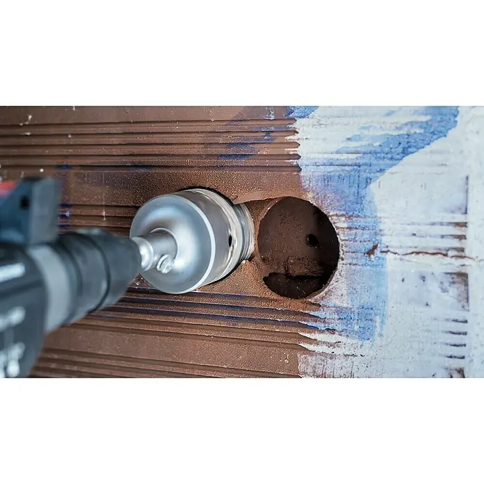 Craftomat Bohrkrone - Durchmesser Bohrer: 82 mm - Ein Bohrer mit einem Lochschneider bohrt ein Loch in eine braune Wand, wobei sich die Drehbewegung des Werkzeugs in Unschärfe zeigt.