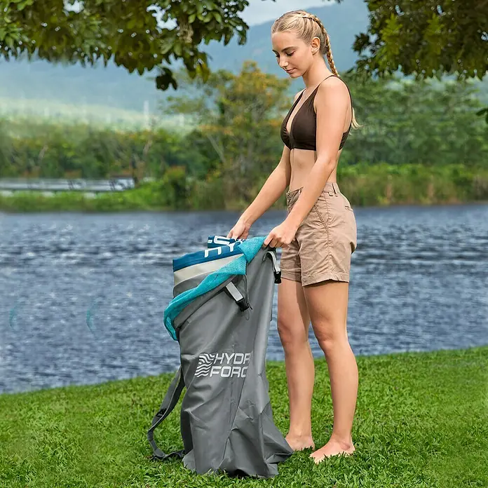 Bestway Hydro Force SUP-Board-Set Aqua Drifter™ mit Sitz - L x B x H: 335 x 91,5 x 15 cm, Nutzlast: 150 kg, Aufblasbar, Grün - Frau mit braunem Bikinioberteil und Cargo-Shorts, die einen grauen Hydr-Force Seesack öffnet.