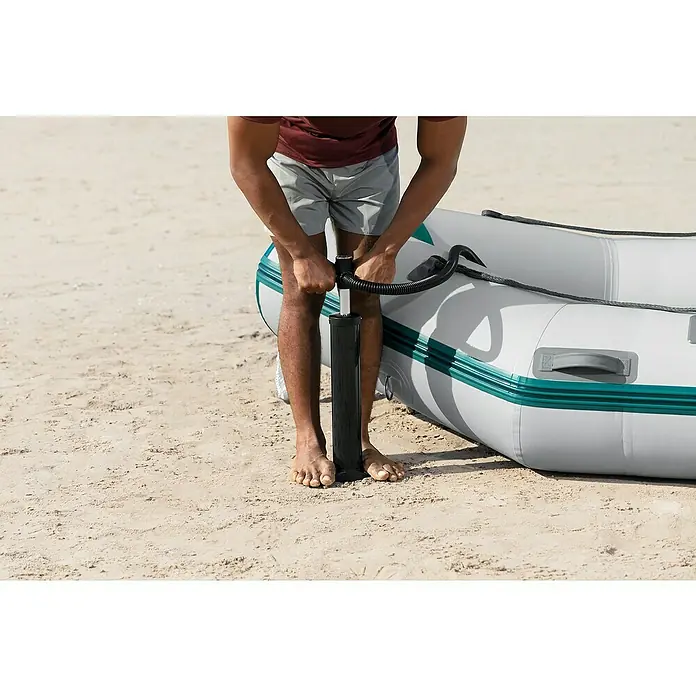 Bestway Hydro Force Schlauchboot-Set Mirovia Pro™ - L x B x H: 330 x 162 x 44 cm, Geeignet für: Max. 5 Personen, Nutzlast: 640 kg - Eine Person pumpt ein graues Schlauchboot mit türkisfarbenen Akzenten am Strand mit einer schwarzen Luftpumpe auf.