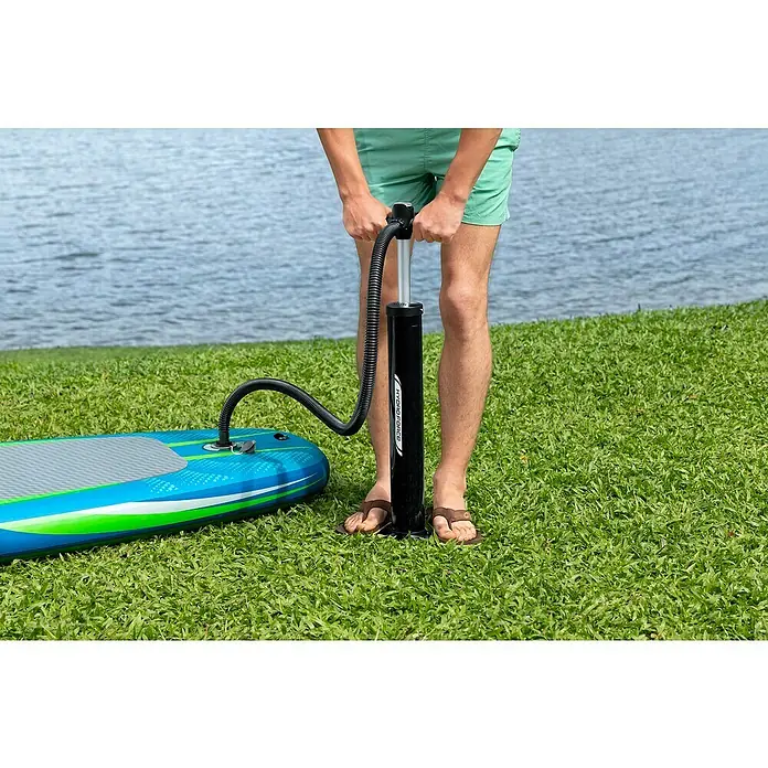 Bestway Hydro Force SUP-Board-Set Aqua Journey - L x B x H: 274 x 76 x 12 cm, Nutzlast: 100 kg, Aufblasbar, Blau/Weiß - Eine Person pumpt ein Hydro-Force-Stand-Up-Paddleboard mit einer schwarzen Hydro-Force-Pumpe auf einer grünen Rasenfläche am Wasser auf.