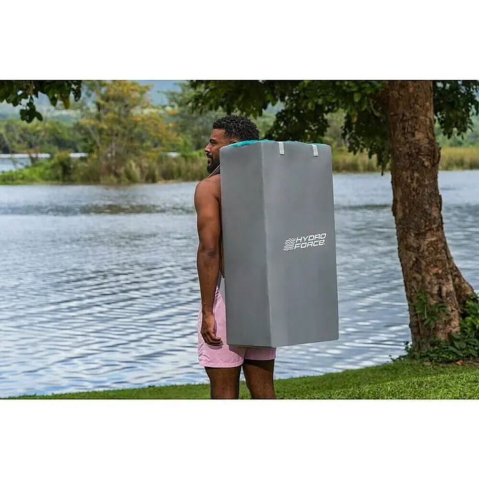 Bestway Hydro Force SUP-Board-Set Aqua Drifter™ View - L x B x H: 335 x 91,5 x 15 cm, Nutzlast: 140 kg, Aufblasbar, Grau/Blau - Ein Mann trägt eine graue Hydro-Force Stand-Up-Paddling-Board-Tasche am See. Die Tasche hat das Hydro Force Logo und türkisfarbene Details.