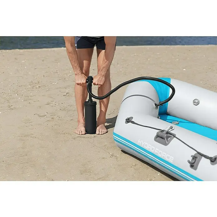 Bestway Hydro Force Schlauchboot-Set Corinth Elite™ - L x B x H: 230 x 130 x 33 cm, Geeignet für: 2 Personen, Nutzlast: 280 kg - Eine Person pumpt ein Hydro-Force-Schlauchboot am Strand auf, wobei der Fokus auf der Pumpe und dem Boot liegt.