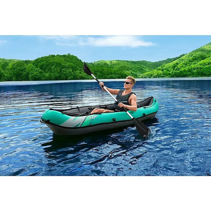 Bestway Hydro Force Kajak Ventura Elite™ X1 - L x B: 280 x 86 cm, Nutzlast: 130 kg, Geeignet für: 1 Person - Ein Mann paddelt mit einem grünen Hydro-Force Kajak auf einem ruhigen See, umgeben von grünen Hügeln.