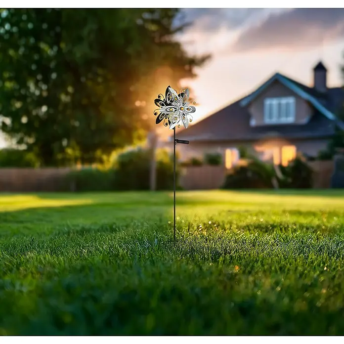 Globo Solar-Dekoleuchte Windrad - 0,02 W, L x B x H: 320 x 175 x 1.240 mm, Silbergrau, IP44 - Eine Nahaufnahme eines dekorativen Windrads mit Solarfunktion im Garten bei Sonnenuntergang.