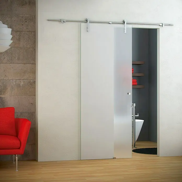Puerta corredera de vidrio Bután Mate - 75 x 210 cm, Vidrio templado - Una moderna puerta corredera de vidrio parcialmente abierta con un elegante accesorio metálico, que ofrece una visión de un baño con inodoro y estantes.