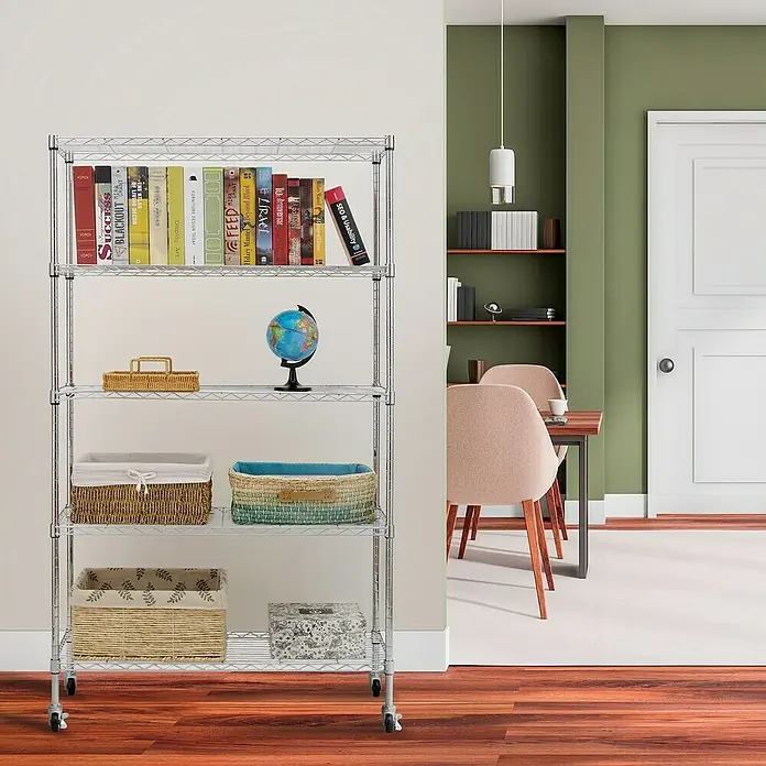 Floordirekt Gitterregal Maya - H x B x T: 150 x 34 x 89 cm, Traglast pro Boden: 24 kg, Anzahl Böden: 5 Stk., Stecken, Chrom - Regal mit fünf Regalböden und Rollen, voll mit Büchern und Körben, in einem Wohnzimmer.