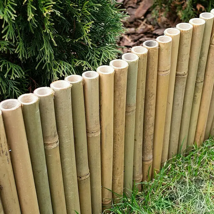 Floordirekt Beeteinfassung - 100 x 20 cm, Bambus - Diese Nahaufnahme zeigt einen dekorativen, niedrigen Bambuszaun im Garten, der als Beetbegrenzung dient. Der Zaun ist aus naturbelassenen Bambusrohren gefertigt.