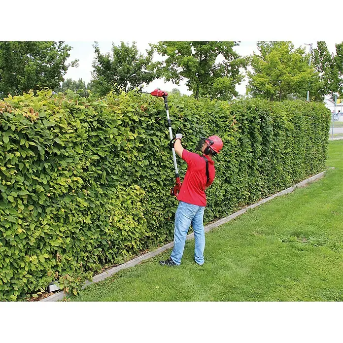 Einhell Power X-Change 18V Akku-Heckenschere GE-HH 18/45 Li T-Solo - 18 V, Li-Ionen, Ohne Akku, Schnittlänge: 40 cm - Eine Person, die mit einer roten Teleskop-Heckenschere eine Hecke schneidet.