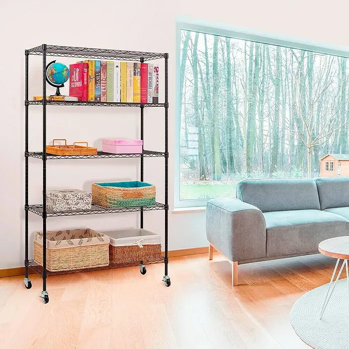 Floordirekt Gitterregal Maya - H x B x T: 150 x 34 x 89 cm, Traglast pro Boden: 24 kg, Anzahl Böden: 5 Stk., Stecken, Schwarz - Ein schwarzes, rollbares Drahtregal mit fünf Ablagen, gefüllt mit Büchern und dekorativen Körben, steht in einem hellen Wohnzimmer.