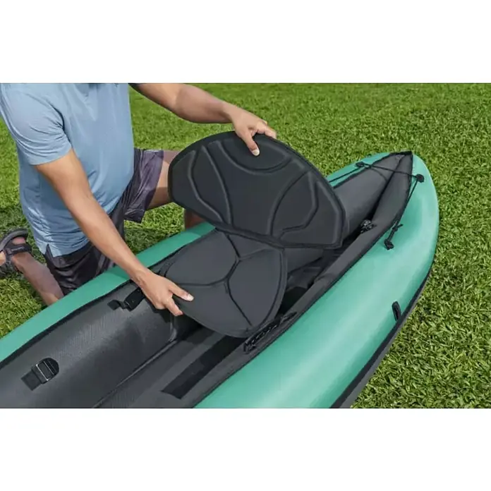 Bestway Hydro Force Kajak Ventura Elite™ X1 - L x B: 280 x 86 cm, Nutzlast: 130 kg, Geeignet für: 1 Person - Eine Person befestigt einen schwarzen Sitz in einem grünen und schwarzen Schlauchboot auf einer Rasenfläche.