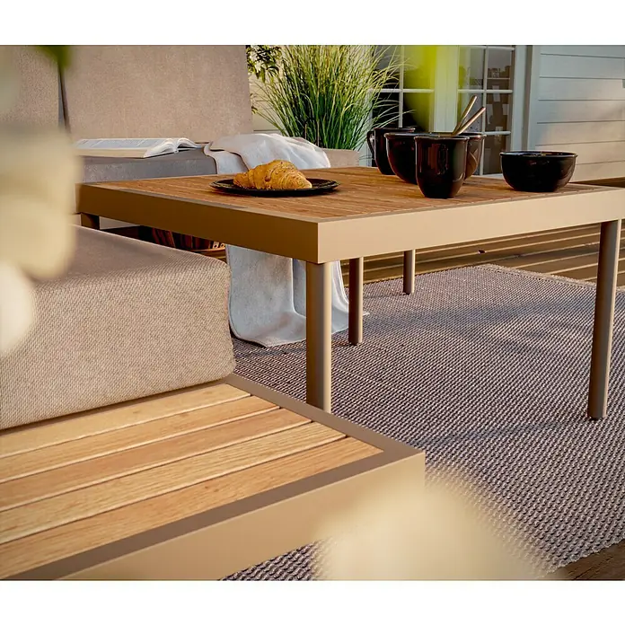 SENSUM Loungemöbel-Set Ankarsvik - 3 -tlg., Aluminium, Teak, Sandbraun - Ein quadratischer Outdoor-Tisch mit einer Schale und Tassen auf einem Gartenteppich, der eine entspannte Atmosphäre für Mahlzeiten im Freien bietet.